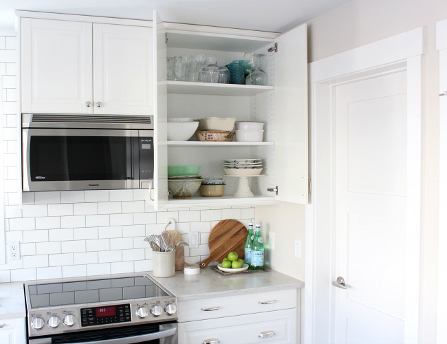 White Kitchen Cupboards With Doors Open to Show Organized Dishes