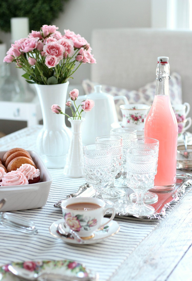 GALentine's Day Tea Party Table Setting with Vintage Floral Tea Cups, Anchor Hocking Stemmed Glasses and Bottle of Pink Lemonade