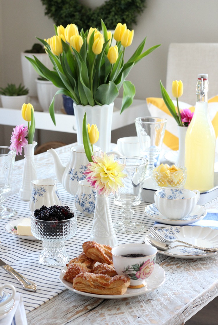 Bright and Cheery Tablescape for Afternoon Tea with Yellow Tulips, Blue and White Floral Tea Cups and Pastries