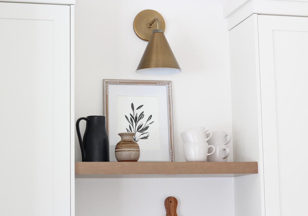 Brass Wall Sconce Above Wood Shelves in Kitchen