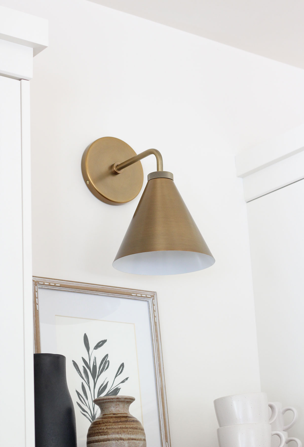 Tapered Brass Sconce Between White Cabinets in Kitchen