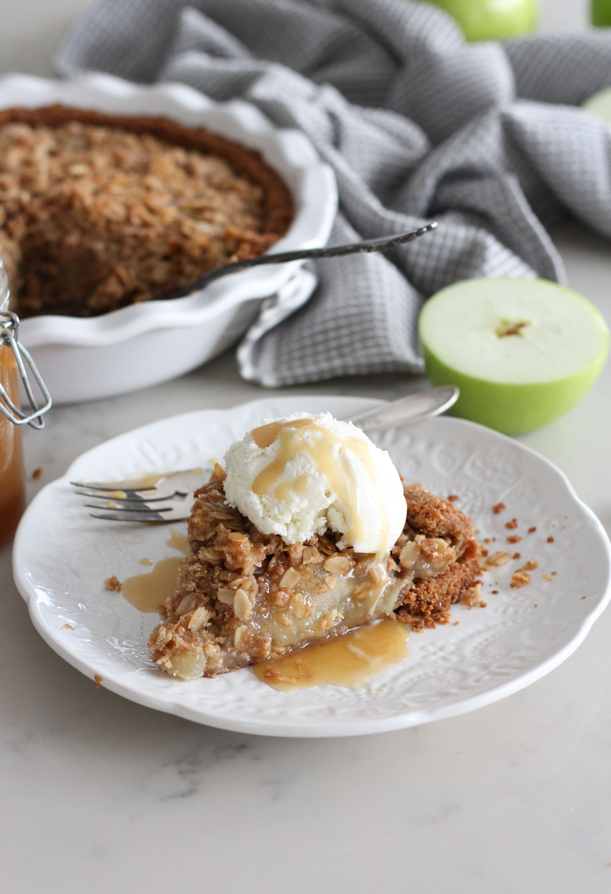Slice of Gluten Free Apple Pie on White Plate Topped with Ice Cream and Salted Caramel