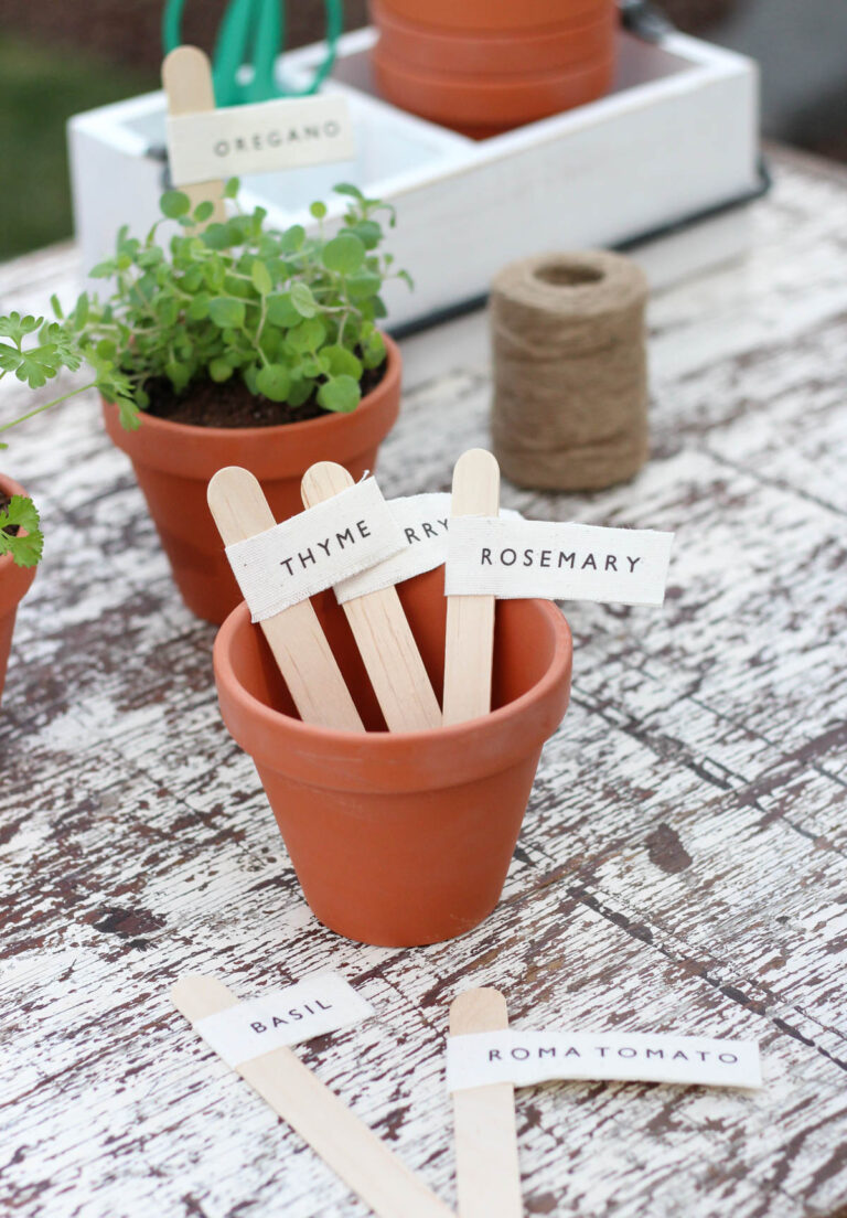 DIY printed garden markers for potted herbs and vegetables made from canvas and transfer paper in a garden setting