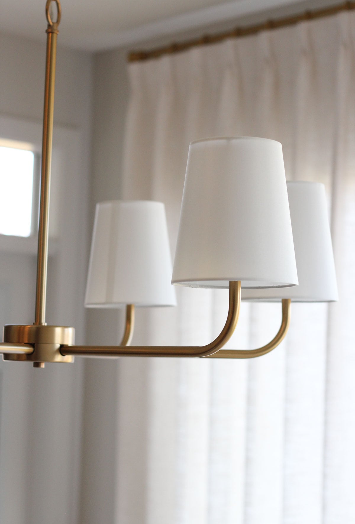 6-light brass chandelier with white shades hanging in dining room