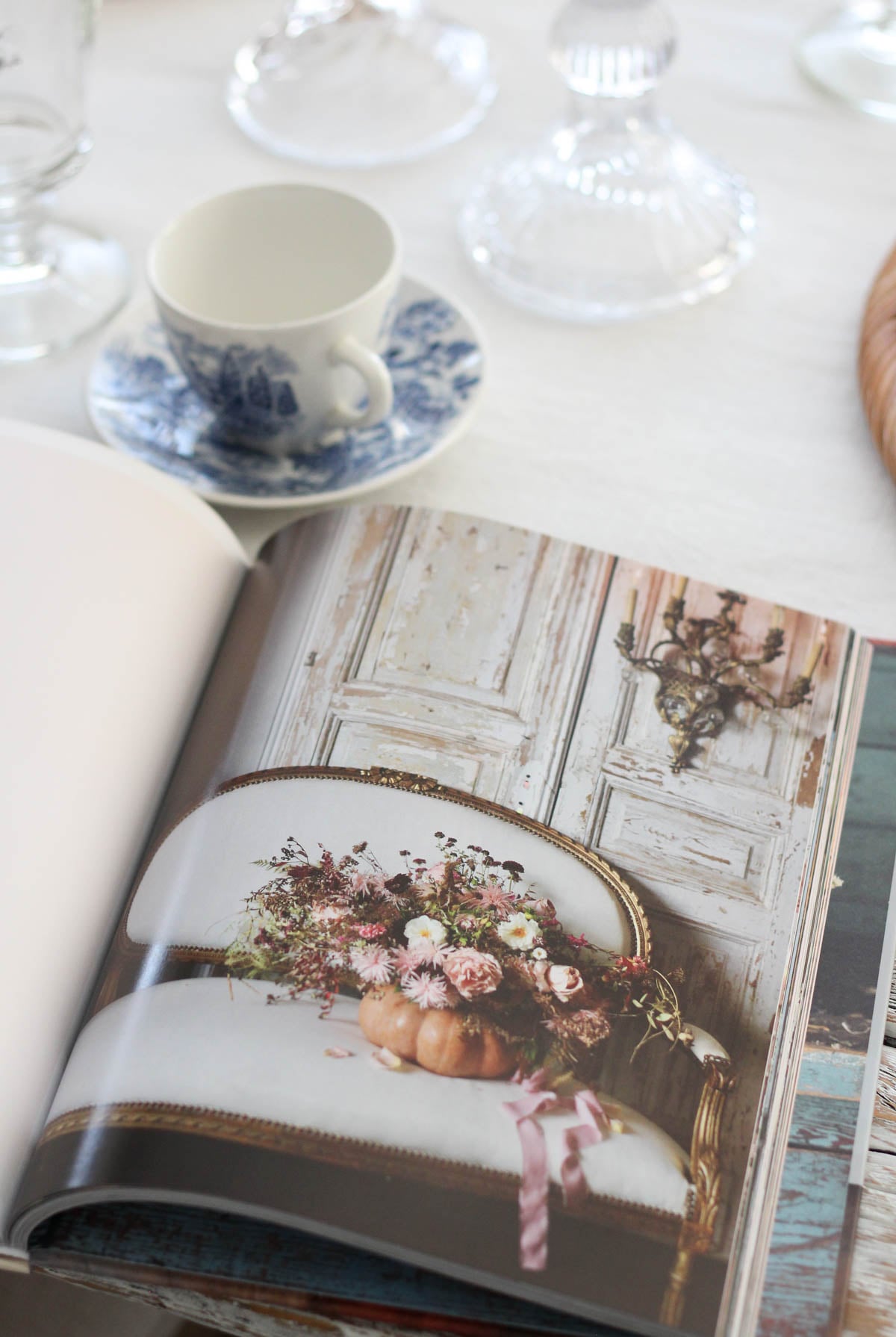Home decor book open on dining table with picture of pumpkin floral arrangement