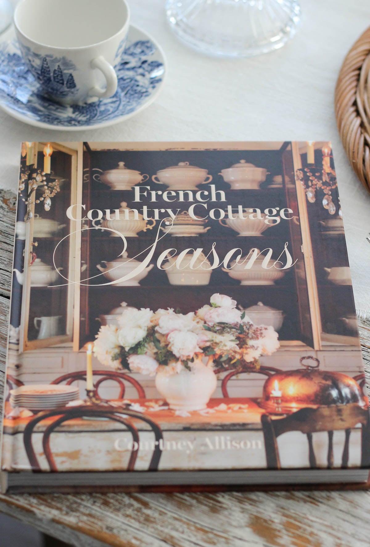 French Country Cottage Seasons book on dining table with vintage blue and white tea cup and saucer