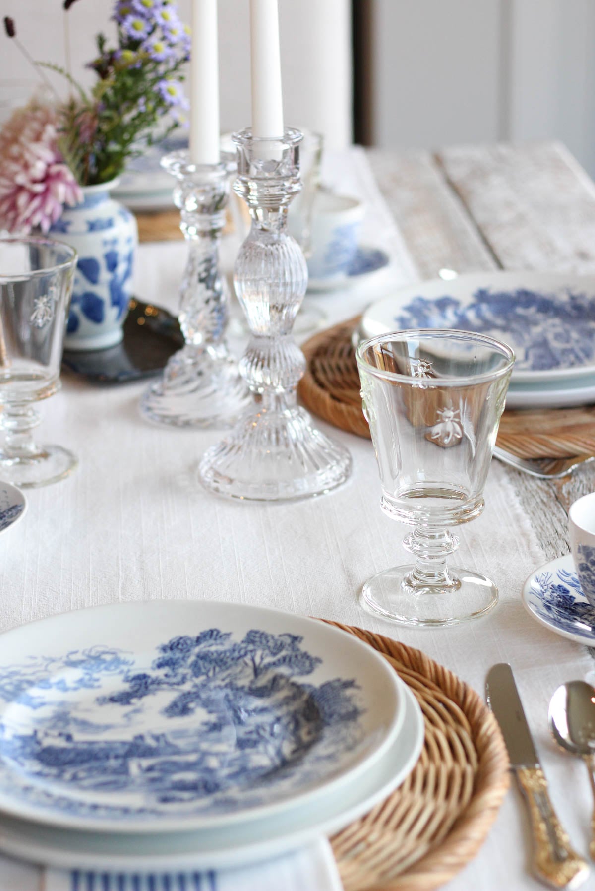 Table set with white table runner, vintage blue and white dishes, and bee glasses